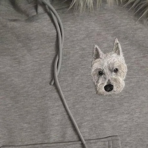 Könnte beinhalten: Grauer Kapuzenpullover mit einem gestickten weißen Hund auf der Vorderseite.