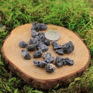 May include: A collection of small, black, and gray, rough, natural, raw, unpolished,  crystals on a wooden surface.