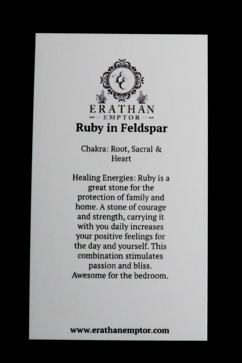 K&ouml;nnte beinhalten: Eine wei&szlig;e Karte mit schwarzem Text und einem Logo, das ein stilisiertes doppeltes 'C' mit einem Kristalldesign zeigt. Der Text lautet "ERATHAN EMPTOR" und "Ruby in Feldspar". Die Karte enth&auml;lt auch Informationen &uuml;ber das Chakra, die heilenden Energien und die Vorteile des Steins.
