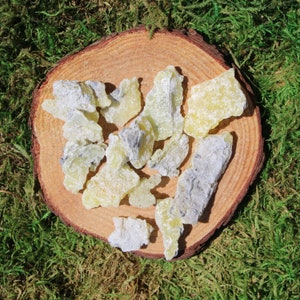 May include: A collection of yellow-green resin pieces with a white powdery coating, arranged on a wooden surface.