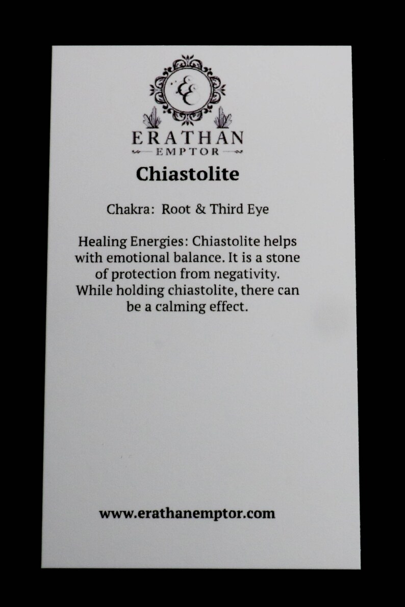 Puede incluir: Una tarjeta blanca con texto negro que describe las propiedades curativas de la chiastolite. La tarjeta tiene el texto "ERATHAN EMPTOR" y "Chiastolite" en la parte superior. El texto dice "Chakra: Ra&iacute;z y Tercer Ojo" y "Energ&iacute;as curativas: La chiastolite ayuda con el equilibrio emocional. Es una piedra de protecci&oacute;n contra la negatividad. Mientras se sostiene la chiastolite, puede haber un efecto calmante." La tarjeta tambi&eacute;n tiene la direcci&oacute;n del sitio web "www.erathanemptor.com" en la parte inferior.