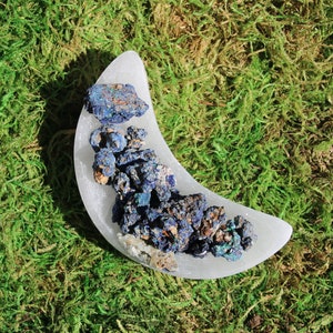 May include: A white crescent moon shaped selenite crystal with a cluster of blue and green azurite crystals on top.