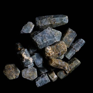 May include: A collection of rough, gray and brown gemstones. The stones are various shapes and sizes, and have a natural, unpolished look.