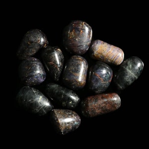 May include: A collection of tumbled stones with iridescent purple, blue, and brown hues. The stones are smooth and polished, with a variety of shapes and sizes.