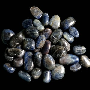 May include: A collection of tumbled blue kyanite stones. The stones are smooth and polished, with a variety of shades of blue.