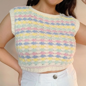 Puede incluir: Un top de crochet de colores pastel con fondo blanco y rayas de color amarillo, azul claro, rosa y verde. El top es sin mangas y tiene un escote redondo.