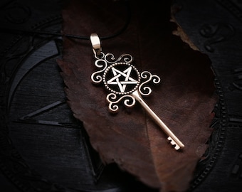 May include: A silver key pendant with a pentagram design. The key is on a brown leather background.