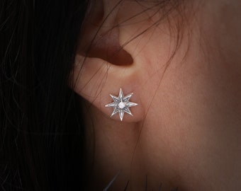 May include: A silver star-shaped earring with a small diamond in the center.