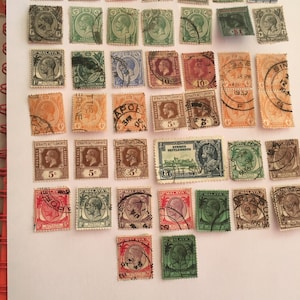 May include: A selection of vintage postage stamps in various colours, including green, red, and blue. The stamps feature portraits, numbers, and text, such as "MALAYA" and "STRAITS SETTLEMENTS". Some stamps have postmarks and are arranged on a white surface.