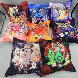 May include: A collection of nine decorative throw pillows with various colorful anime-style character designs. The pillows feature a variety of colors, including red, blue, orange, pink, purple, and black. Each pillow has a unique design with detailed illustrations.
