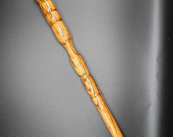 May include: A wooden wand with a brown and light brown striped pattern. The wand has a rounded tip and a slightly thicker handle.