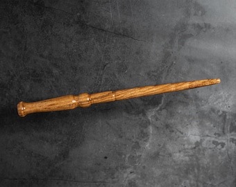 May include: A wooden wand with a brown finish. The wand is about 12 inches long and has a slightly curved tip.