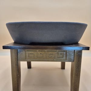 Könnte beinhalten: Ein Set aus drei Keramikbechern mit gesprenkelter, matter Oberfläche. Die Becher sind in Creme-, Hellgrau- und Dunkelgrautönen gehalten. Jeder Becher hat ein schlichtes, minimalistisches Design.