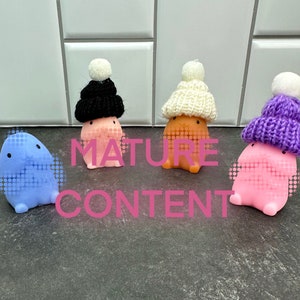 May include: Four colorful, rounded figurines with small knitted hats and pom-poms. The figurines are blue, pink, orange, and pink with black, white, orange, and purple hats. The text "MATURE CONTENT" is printed across the image.
