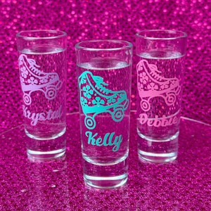 May include: Three clear glass shot glasses with pink and teal roller skate designs and personalised names: "Krystal", "Kelly", and "Debbie".