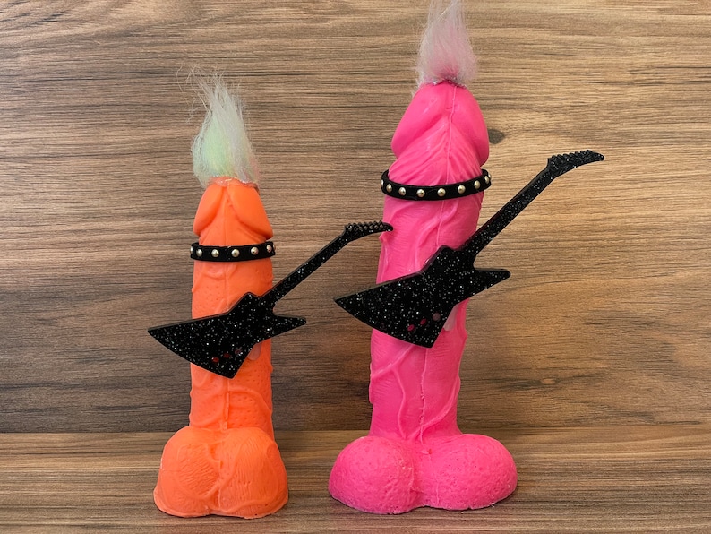 May include: Two colourful, anthropomorphic figures with hair and a black guitar. The figure on the left is orange and the figure on the right is pink.