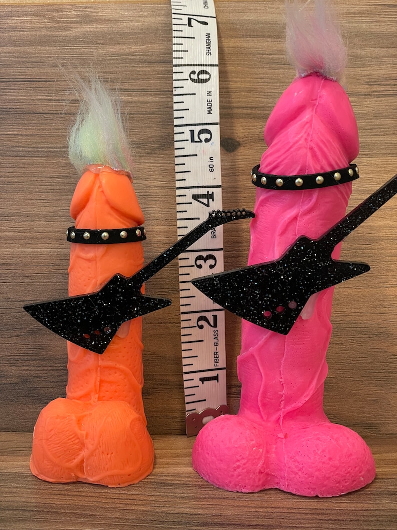 May include: Two novelty figures, one pink and one orange, each holding a black glitter guitar and wearing a studded belt. The figures are approximately 5 inches tall.