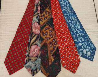 May include: Five neckties with various patterns are displayed. The ties include a red tie with a repeating square pattern, a floral tie with pink flowers, a paisley tie, a red tie with a butterfly pattern, and a blue tie with a white floral design.