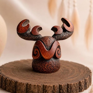 Peut inclure: Sculpture en bois représentant un élan stylisé, de couleur marron foncé. Les bois sont courbés et détaillés. La sculpture est posée sur une base ronde en bois brut. Objet décoratif artisanal.