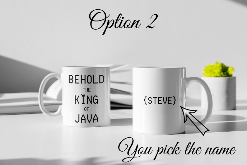 以下が含まれることがあります： 白いコーヒーカップが2つ。1つのカップには「Behold the King of Java」と書いてあり、もう1つのカップには名前のプレースホルダー「{STEVE}」があります。「You pick the name」というテキストがカップの下にあります。