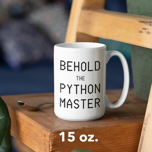 Puede incluir: Taza de cer&aacute;mica blanca con texto negro que dice "Behold the Python Master". La taza es de 15 onzas y est&aacute; sobre una superficie de madera.