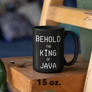 以下が含まれることがあります： 黒いセラミック製のマグカップに、白い文字で「Behold the King of Java」と書いてあります。マグカップは15オンスです。