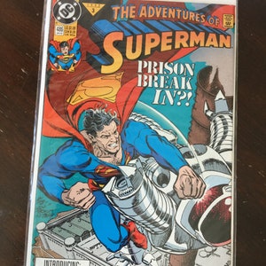May include: A comic book titled "The Adventures of Superman" features Superman in a dynamic pose. The cover art showcases Superman in a blue suit and red cape, with the text "Prison Break In?!" and "Introducing: The Purge of Metropolis!"