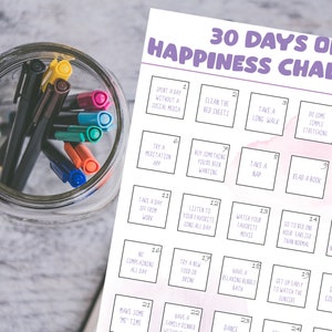 May include: A printable 30-day happiness challenge checklist with a pink watercolor background. The checklist includes activities such as taking a long walk, reading a book, and trying a new food.