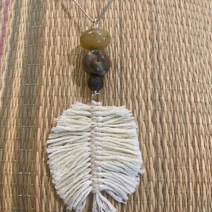 Może przedstawiać: Naszyjnik z białym frędzlowym wisiorem w kształcie pióra i brązowymi i beżowymi koralikami.