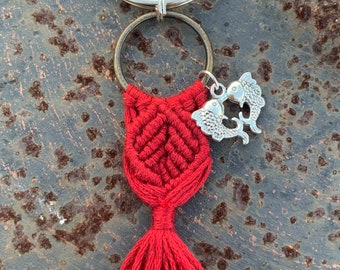 May include: Red macrame keychain with a silver tassel and two silver fish charms attached to a silver key ring.