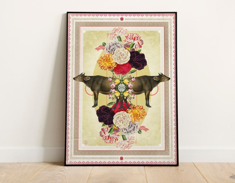 Op de afbeelding: Ingelijste kunstdruk met twee bruine waterbuffels die tegenover elkaar staan, omringd door kleurrijke bloemen. Het kunstwerk heeft een cr&egrave;mekleurige achtergrond met een decoratieve rand en een zwart frame.