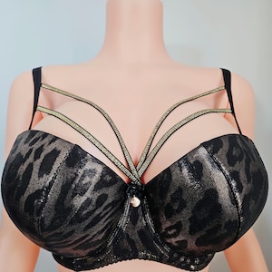May include: Black and gold leopard print bra with multiple straps. The bra features a decorative center and adjustable straps. The bra is displayed on a mannequin.