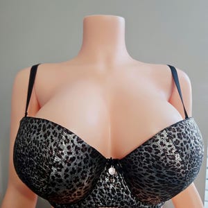 May include: A black and silver leopard print bra with adjustable straps. The bra features a center embellishment and is displayed on a mannequin. The bra has a push-up design.