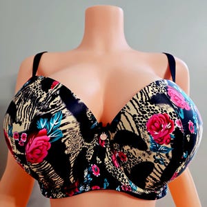 May include: A full-coverage bra with a floral and animal print design. The bra features a black base with pink roses, blue accents, and a tan and black animal print. It has adjustable straps and a center clasp.