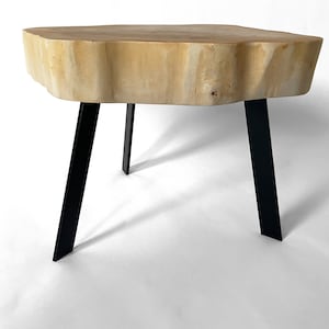 Peut inclure: Une table basse en bois naturel avec un plateau en bordure brute et des pieds en métal noir.