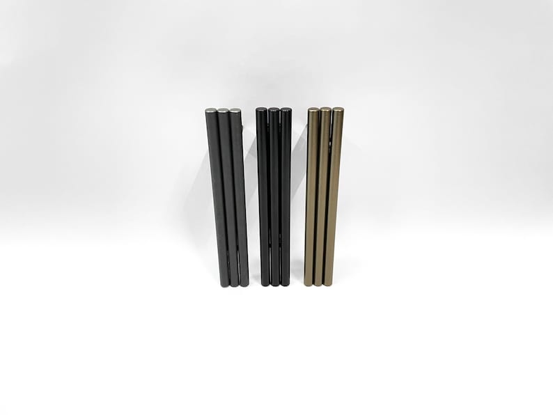 Puede incluir: Tres juegos de varillas met&aacute;licas en negro, gris oscuro y dorado. Cada juego consta de tres varillas apiladas una encima de la otra.