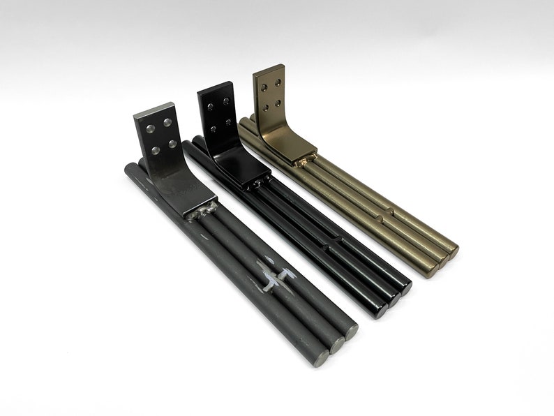 Puede incluir: Tres soportes met&aacute;licos con tres varillas met&aacute;licas unidas a cada uno. Los soportes son de diferentes colores: dorado, negro y gris.