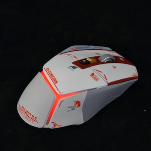 May include: A white and red gaming mouse with a red light on the side. The mouse has the text "Project U.C." and "RX-9 Unicorn" on it.