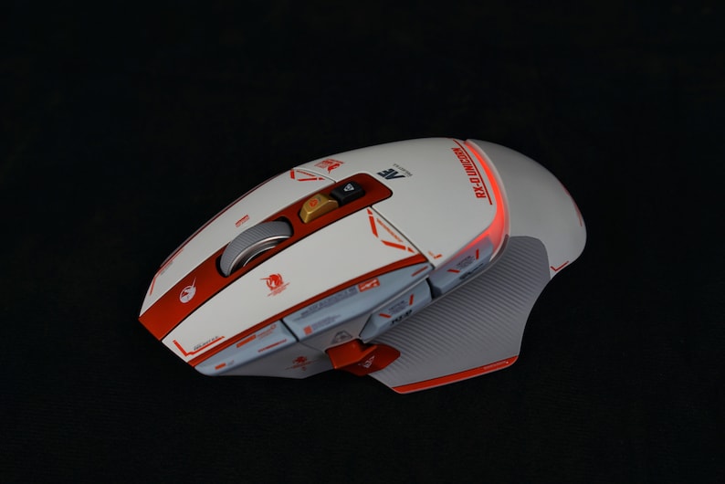 May include: A white and red gaming mouse with a textured surface and a red light on the side. The mouse has multiple buttons and a scroll wheel. The text "RX-0 Unicorn" is printed on the side of the mouse.