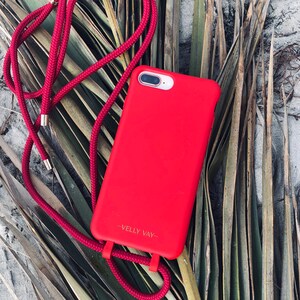 May include: A red phone case with a red phone strap. The case has the text "VELLY VAY" printed on it.