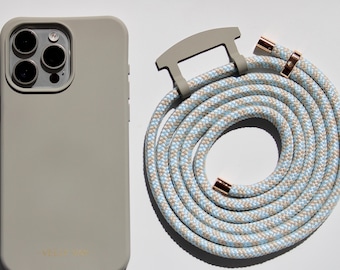 May include: A light gray phone case with a matching rope strap. The rope strap is a mix of light blue, beige, and white. The phone case has a camera and flash. The strap has rose gold accents.