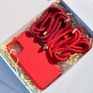May include: A red phone case with the text "Welly Way" on the back, and two red phone straps with gold accents in a white box with shredded paper.