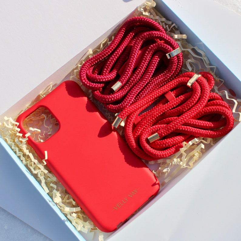 May include: A red phone case with the text "Welly Way" on the back, and two red phone straps with gold accents in a white box with shredded paper.
