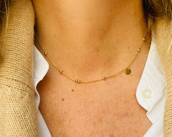 May include: A gold chain necklace with small round beads and a small round pendant.