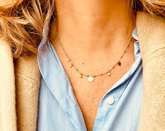 May include: A gold necklace with a delicate chain and small round charms. The necklace features a larger round charm in the center.