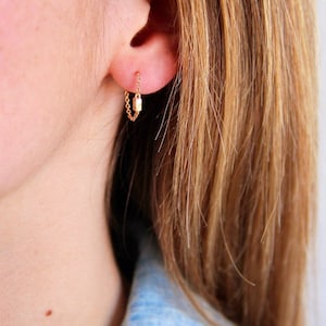 May include: Gold chain earrings with a small rectangular charm hanging from the bottom of the chain.