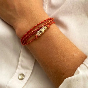 Kuta, a Balinese lucky charm, can be worn as a triple-wrapped bracelet or as a necklace, thanks to a cotton cord and gold-plated finishes.