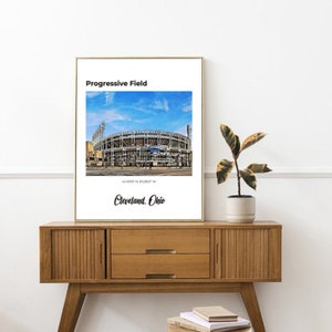 May include: A white framed print with a photo of Progressive Field, a baseball stadium in Cleveland, Ohio. The text "Progressive Field" is at the top of the print, and the text "Cleveland, Ohio" is at the bottom.