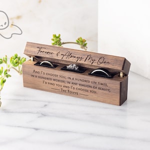 May include: A wooden ring box with a hinged lid, engraved with the text "Forever & Always My One" and a romantic message. The box has three compartments for rings.