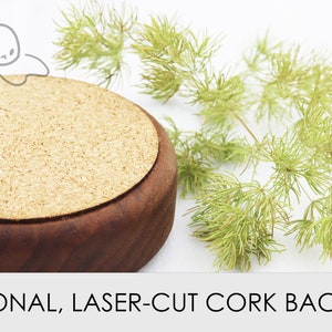 May include: A round, wooden coaster with a cork backing. The coaster is brown and has a natural wood finish. The cork backing is a light brown color and has a slightly rough texture.